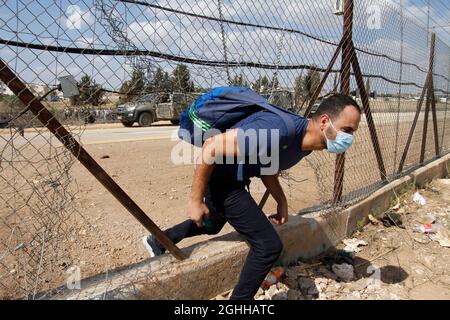 Djénine, Palestine. 06e septembre 2021. Un palestinien traverse la section endommagée du mur de séparation israélien près de la ville de Djénine en Cisjordanie.six prisonniers palestiniens ont échappé lundi à la prison en Israël, menant à une chasse à l'homme généralisée, ont déclaré les autorités israéliennes. La police a déclaré dans une déclaration que l'évasion extrêmement rare a eu lieu pendant une nuit à la prison de Gilboa, une prison à sécurité maximale pour les prisonniers palestiniens dans le nord d'Israël. Crédit : SOPA Images Limited/Alamy Live News Banque D'Images