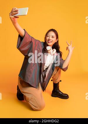 Photo en studio d'une jeune femme à la mode tenant un smartphone Banque D'Images