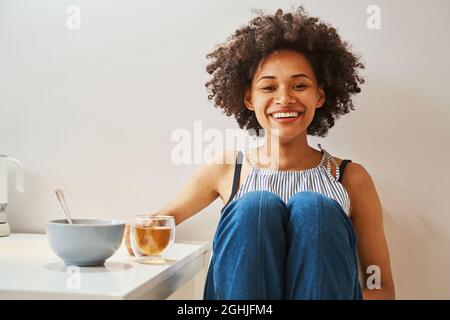Agréable femme très animée avec une boisson à base de plantes à l'approche Banque D'Images
