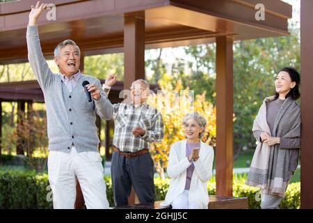 Homme de haut niveau gai chantant avec microphone Banque D'Images