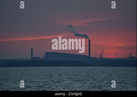 Vue en téléobjectif d'un coucher de soleil rouge épique sur le port de Dublin et l'usine de Covanta (Dublin Waste to Energy) vue depuis la jetée ouest du port de Dun Laoghaire, Dublin Banque D'Images
