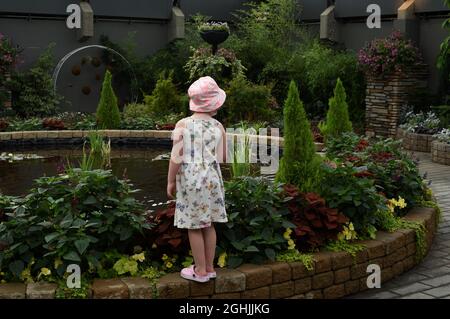 Une jeune fille, portant un chapeau et une robe d'été, regarde un exposé dans les jardins botaniques et le centre horticole du Muttart Conservatory à Edmonton, Banque D'Images