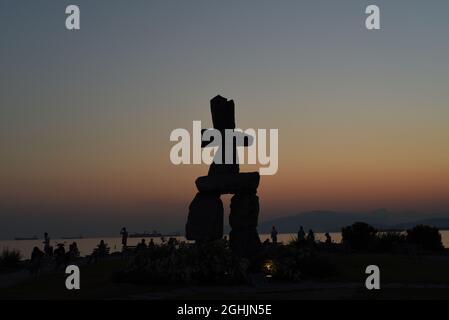 Le soleil se couche sur la baie English et une sculpture silhouetée d'un Inukshuk, un marqueur inuit ou un dispositif de navigation, à Vancouver, en Colombie-Britannique, à Cana Banque D'Images