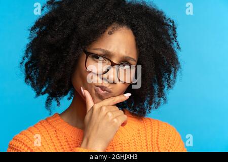 Femme africaine pensive pensant regarder loin toucher la main sur le menton ponder prendre la décision sur le mur de studio Banque D'Images