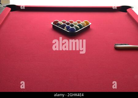 boules de billard dans un rack de boules noires sur une table de billard rouge Banque D'Images