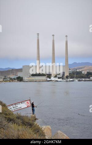 Les gens pêchent à l'entrée de Morro Bay, avec la centrale électrique désaffectée à l'arrière - bonne pêche pour les touristes, San Luis Obispo County, CA Banque D'Images