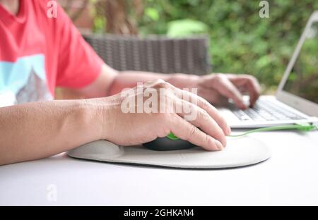 Les doigts de l'homme cliquent sur la souris, reposant son poignet sur le repose-poignet. Gros plan. Banque D'Images