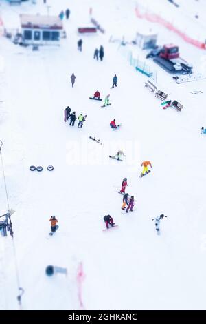 Les gens sont sur une pente enneigée. Les snowboarders et les skieurs passent dans la neige à la station d'hiver. Banque D'Images