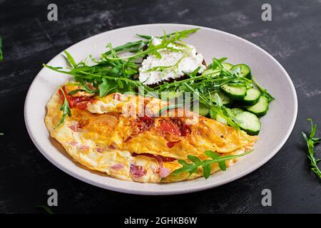 Petit déjeuner. Omelette avec tomates, fromage et salade sur plaque blanche. Frittata - omelette italienne. Banque D'Images