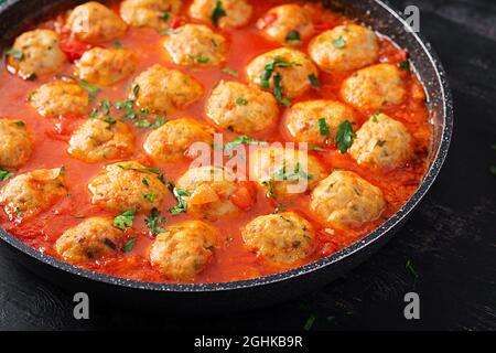 Boulettes de viande en sauce tomate dans une poêle sur fond sombre. Banque D'Images