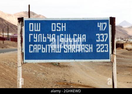 Panneau avec distance à trois villes en cyrillique et romain - 'Osh' 'Gulcha' et 'Saritash' - route de Pamir ou Pamirskij trakt, Kirghizistan et Tajikist Banque D'Images