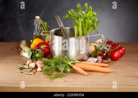 Sélection saine de légumes frais crus pour préparer un ragoût ou une soupe disposés sur une table de cuisine autour d'une grande casserole en acier inoxydable Banque D'Images