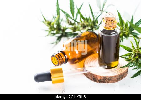 Huile de CBD en bouteilles de verre et feuilles de cannabis à la table blanche. Banque D'Images
