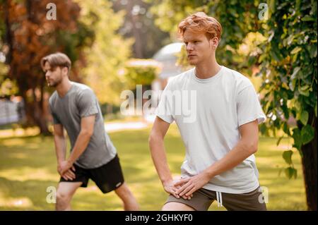 Les gars dans les vêtements de sport faisant des exercices dans la nature Banque D'Images