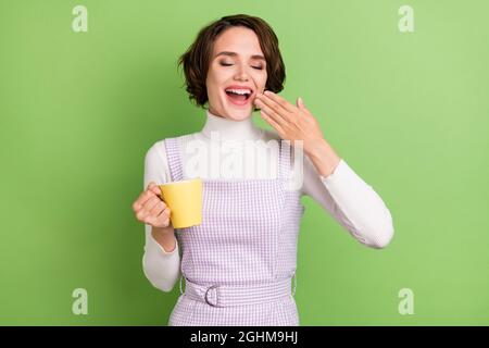 Photo de jeune fille heureux positif sourire endormi matin yawn boire café isolé sur fond vert Banque D'Images