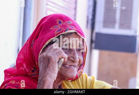 Gros plan sur une femme d'un vieux village indien qui prend un appel au téléphone tout en souriant. Banque D'Images
