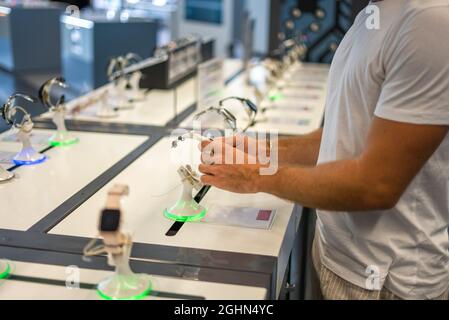 Vue latérale d'un client masculin méconnaissable se trouvant près de la vitrine et vérifiant la montre intelligente lors de ses achats dans un magasin d'électronique moderne Banque D'Images