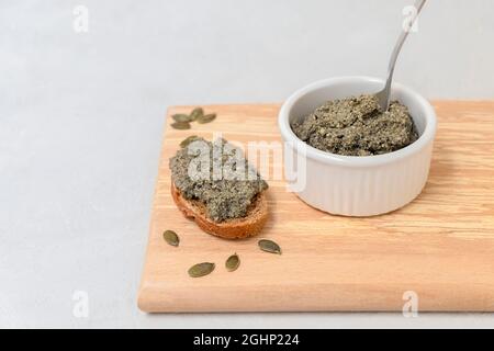 Pâte de fromage végétalien de culture probiotique à base de graines de citrouille, répartie sur une tranche de pain avec espace de copie Banque D'Images