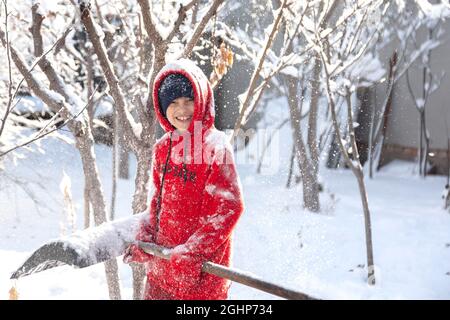 Portrait d'hiver extérieur d'un petit enfant heureux en bonne santé avec une pelle en main, déneigement Banque D'Images