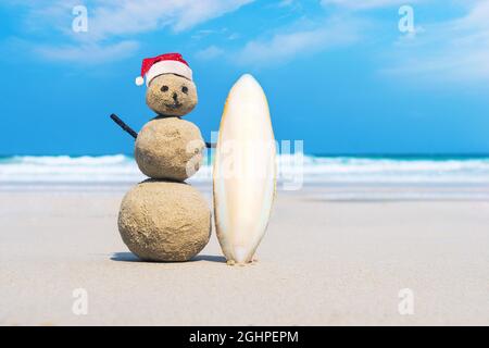 Sandman joyeuse de sable blanc sur la plage propre d'une île exotique sur le fond bleu mer et ciel nuageux. Sand surfeur. idée créative de surfin Banque D'Images