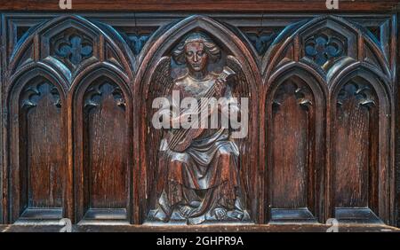 Panneau en bois sculpté (d'un ange avec un instrument de musique) sur une cabine dans le choeur de la cathédrale de Lincoln, en Angleterre. Banque D'Images