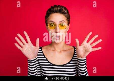 Photo portrait femme portant un verre de soleil stupéfait regarder la bouche ouverte isolé couleur rouge vif arrière-plan Banque D'Images