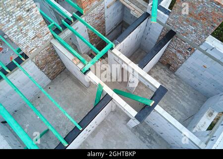 Vue aérienne du cadre inachevé de la maison privée avec murs en béton léger aéré et poutres de toit en bois en construction. Banque D'Images