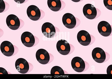 Ancien vinyle noir avec étiquette orange Clean isolée sur fond rose pastel. Concept créatif de modèle de musique rétro. Son Gramophone. DJ Turntab Banque D'Images