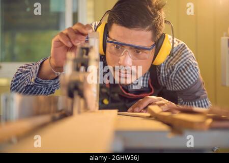 Portrait d'un charpentier à l'aide d'une scie circulaire dans un atelier, Thaïlande Banque D'Images