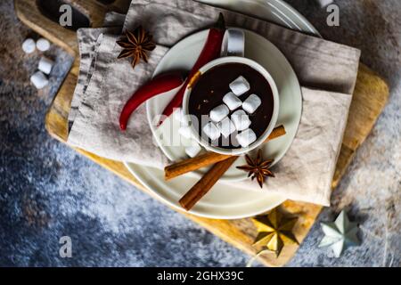 Tasse de chocolat chaud au Chili avec guimauves miniatures sur une planche à découper avec une sélection d'épices Banque D'Images