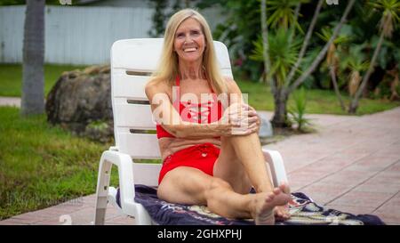 Femme sénior en bonne santé assise au bord de la piscine Banque D'Images