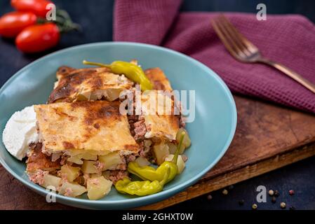 Repas traditionnel des Balkans moussaka dans une assiette sur table de cuisson avec sauce au yaourt Banque D'Images