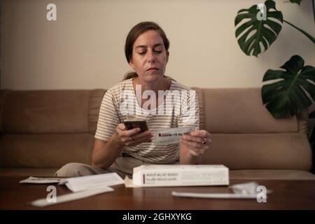 La femme lit les instructions avant d'effectuer un auto-test Covid-19 à la maison Banque D'Images