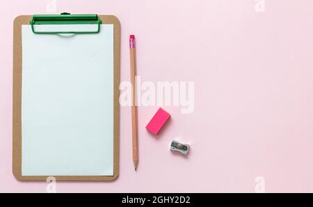 Fournitures scolaires, bureau de l'étudiant, presse-papiers pour papier vierge, gomme à crayon et taille-crayons sur fond rose, espace de copie, modèle. Banque D'Images