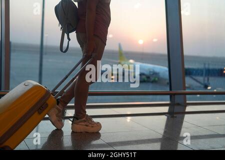 fille avec une valise jaune debout à l'aéroport et attendant l'avion Banque D'Images