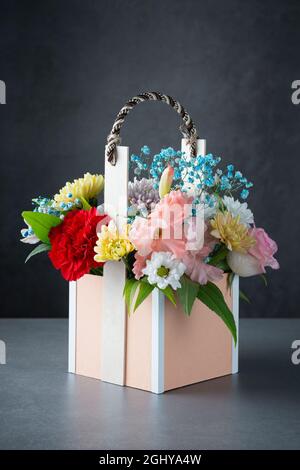 Bouquet frais et luxuriant de fleurs colorées dans un panier sur fond gris Banque D'Images