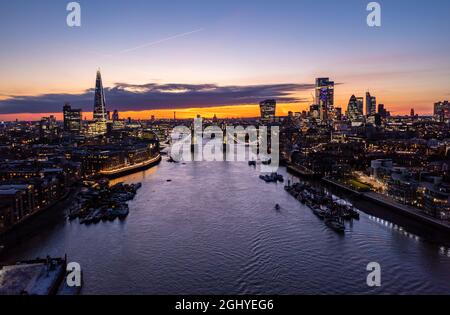 Vue aérienne du célèbre Tower Bridge sur l'océan entouré de bâtiments et de gratte-ciels sous un crépuscule nuageux et un ciel orange crépuscule le matin Banque D'Images