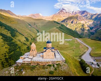 Vue aérienne rapprochée de la montagne Kazbek et de l'église de la Trinité de Gergeti en Géorgie au lever du soleil en été Banque D'Images