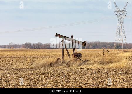 Ancienne pompe de puits de pétrole orpheline dans le champ agricole. Abandon de puits de pétrole, désaffectation, et concept de production de pétrole. Banque D'Images