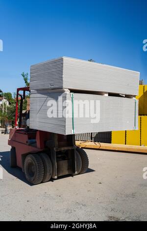 Gros plan sur un élévateur à fourche, transportez la pile de plaques de plâtre sur le palet Banque D'Images