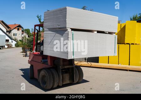 Gros plan sur un élévateur à fourche, transportez la pile de plaques de plâtre sur le palet Banque D'Images