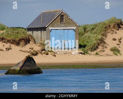 Humble cabane avec de vieilles portes peintes en bleu à la plage de Newburgh Seal en Écosse, par une journée ensoleillée Banque D'Images