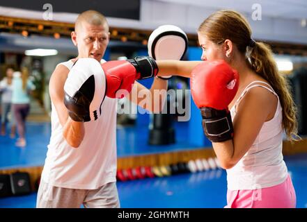 Jeune femme pratiquant des coups de boxe en couple avec un instructeur Banque D'Images