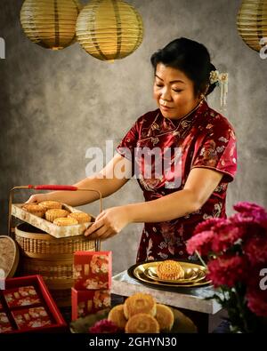 Une dame Peranakan chinoise qui tient un plateau de gâteaux de lune pour le festival de la mi-automne Banque D'Images