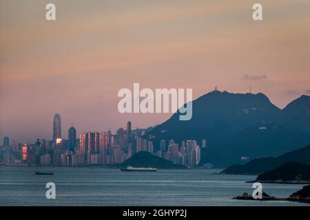 Le soleil couchant se reflétait dans les gratte-ciel de l'île de Hong Kong, avec un ciel rose en raison du phénomène de la « ceinture de Vénus » Banque D'Images