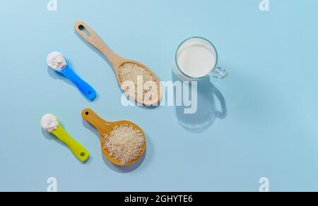 Lait de riz végétalien en poudre. Un verre de lait sur fond multicolore Banque D'Images