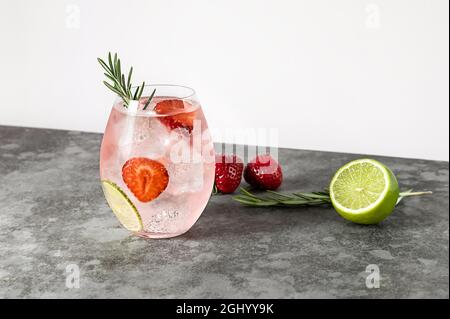Cocktail de gin rose aux fraises et au romarin, boisson alcoolisée rafraîchissante avec glace et citron vert. Banque D'Images