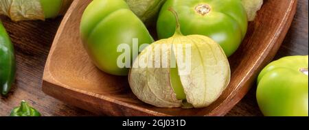 Panorama de tomatillos. Tomates vertes, ingrédients alimentaires mexicains sur fond de bois rustique foncé Banque D'Images