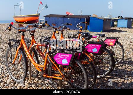 Location de vélos de Donkey Republic un service global de partage de vélos sur Worthing East Beach avec des bateaux de pêche locaux en bois sur East Beach. Banque D'Images