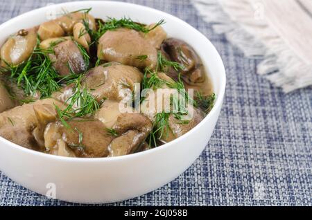 Champignons marinés dans un bol en céramique blanche avec aneth. Le blanc Banque D'Images